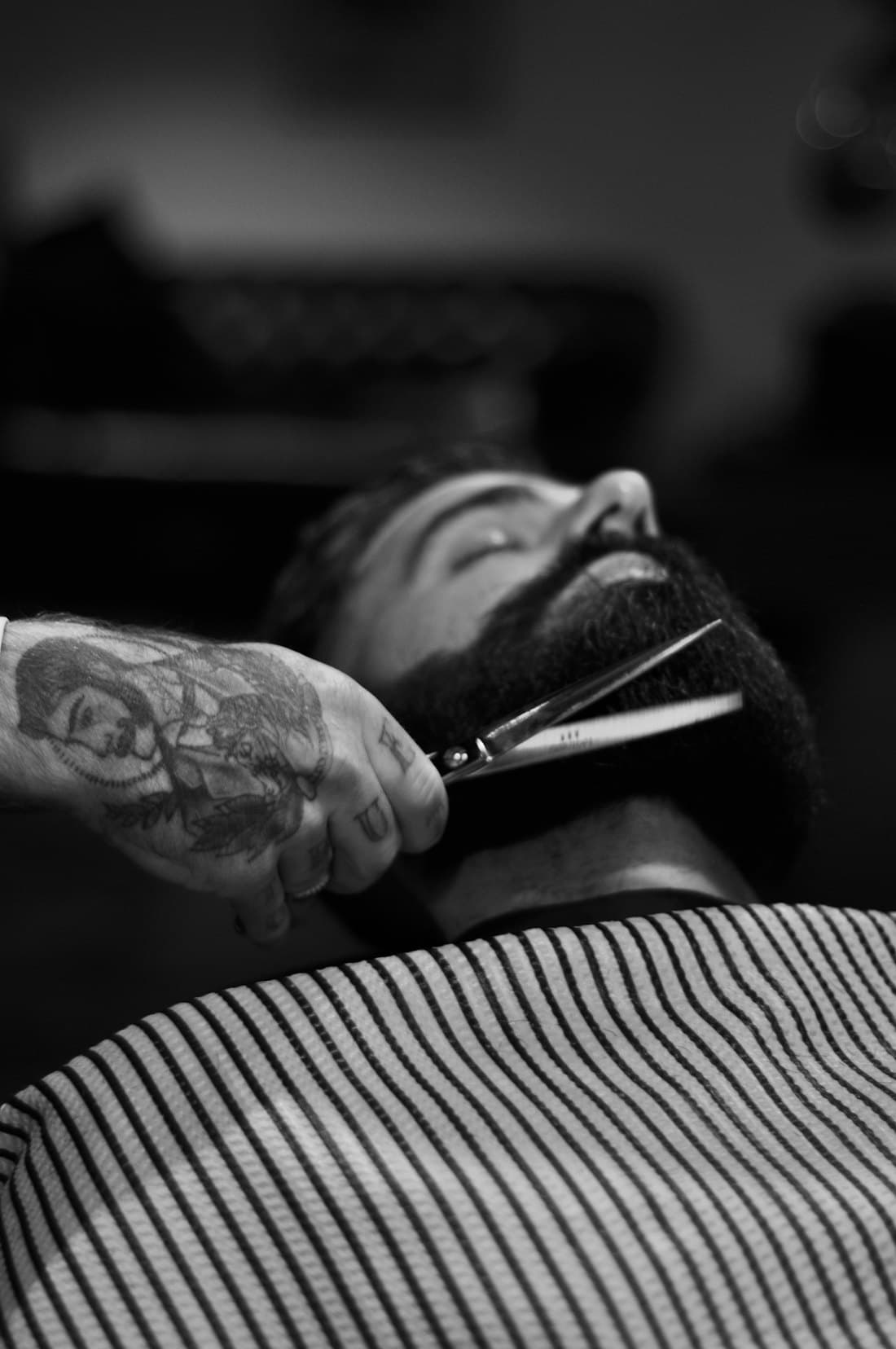 Barbeiro aparando a barba de um cliente